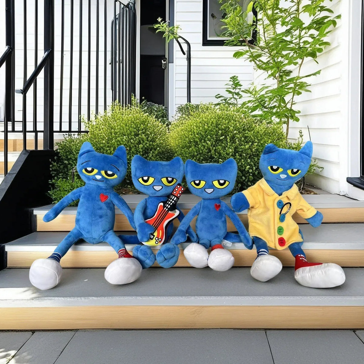 A set of four blue cartoon cat plush toys with different outfits sitting on outdoor steps.