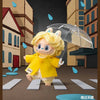 A yellow Labubu vinyl plush pendant with blonde hair is holding a clear umbrella in a dark setting.