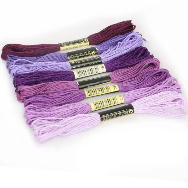 A set of multicolor embroidery floss skeins featuring various shades of purple and pink with a glitter finish.