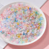 A bowl filled with a colorful gradient mix of pink, blue, and yellow acrylic beads for jewelry making