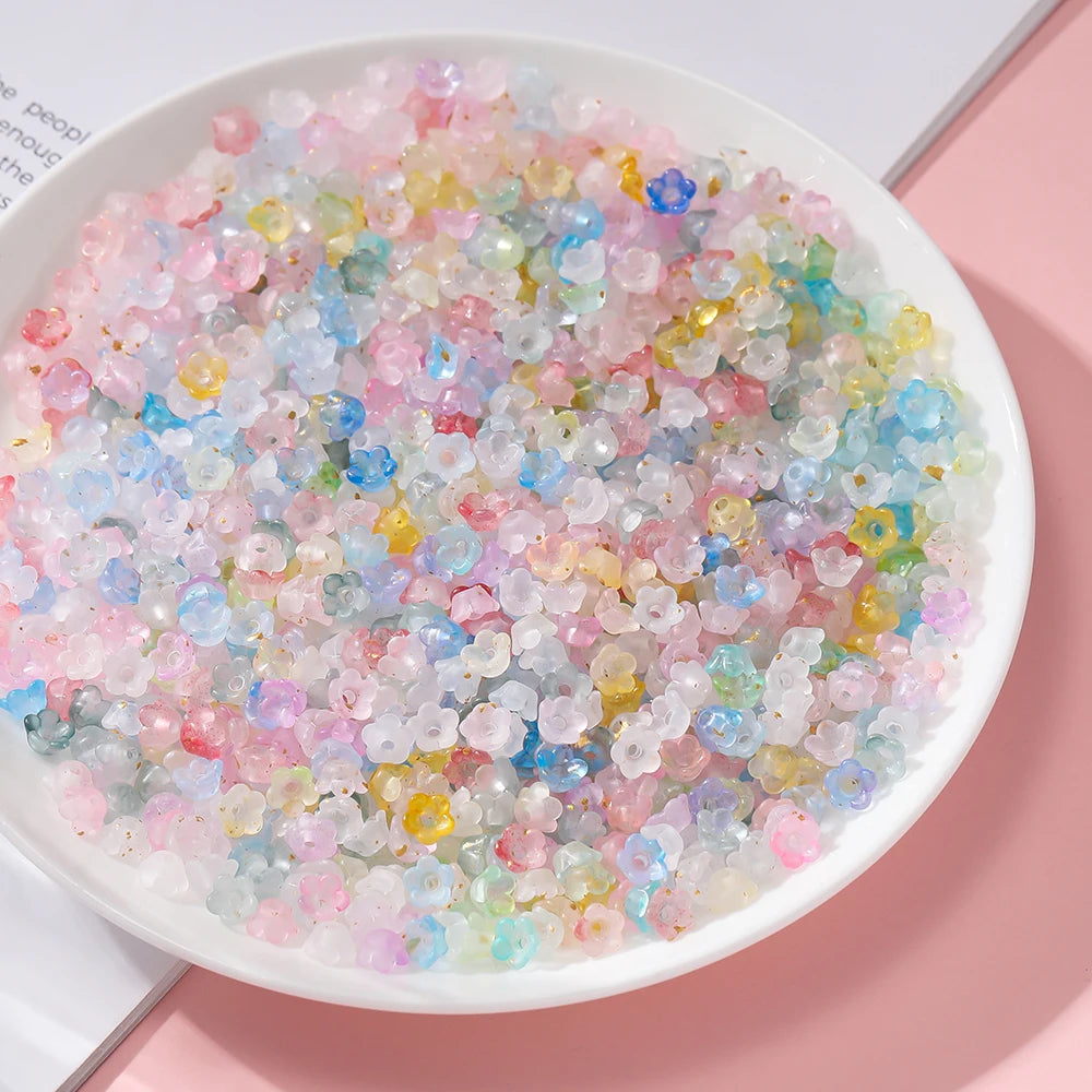 A bowl filled with a colorful gradient mix of pink, blue, and yellow acrylic beads for jewelry making