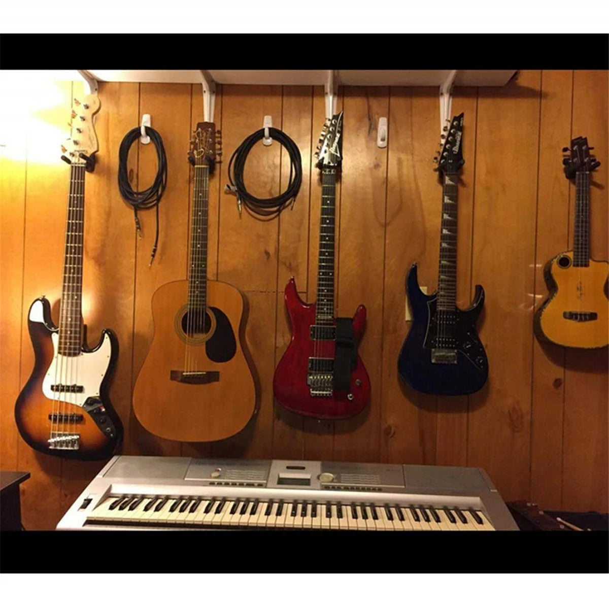 A collection of electric guitars are hanging on a wooden wall, with an acoustic guitar and several electric guitars visible.