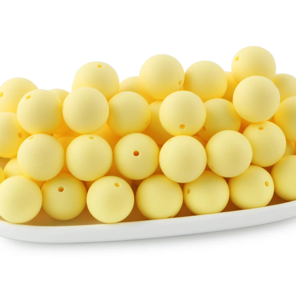 A row of round, pale yellow silicone beads for jewelry making and DIY crafts.