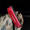 A red 10-hole diatonic harmonica with a black carrying case resting on rough wood.