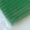 A close-up view of a green polymer clay kit with soft modeling clay visible beneath clear plastic packaging.