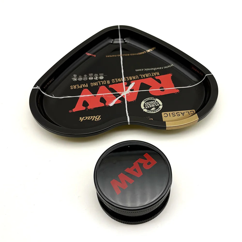 A black love-shaped metal rolling tray with a lid and a separate black grinder is shown on a white background.