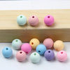 A collection of matte acrylic beads in various pastel colors including pink, blue, green, and yellow resting on a wooden surf