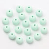 A collection of light mint green matte acrylic beads for jewelry making arranged in a loose circle.