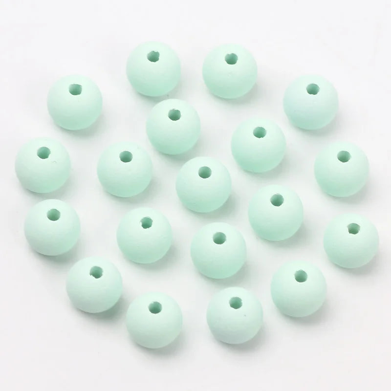 A collection of light mint green matte acrylic beads for jewelry making arranged in a loose circle.