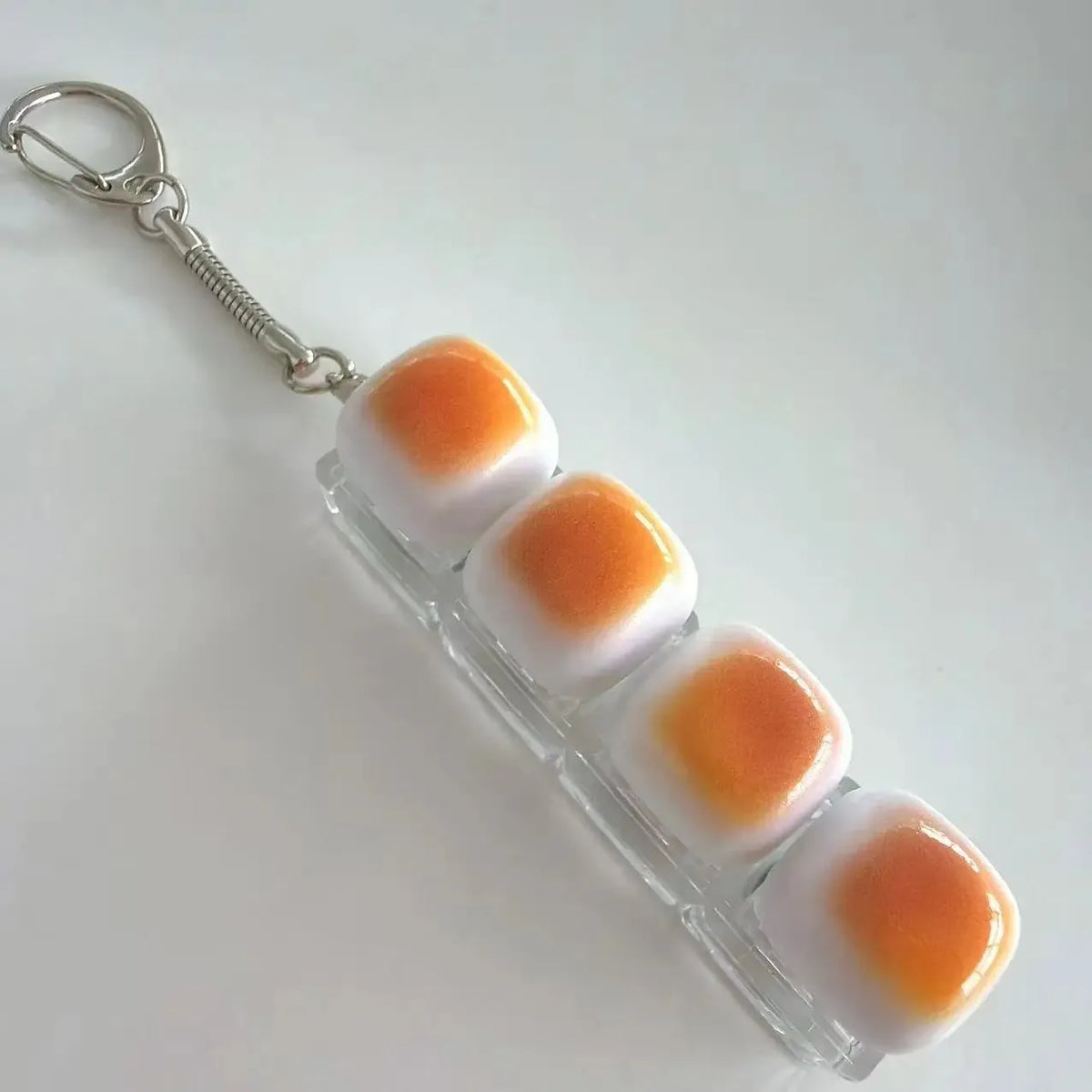 A clear plastic keychain featuring several white and orange silicone fidget beads attached to a metal ring.