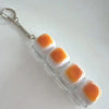 A clear plastic keychain featuring several white and orange silicone fidget beads attached to a metal ring.