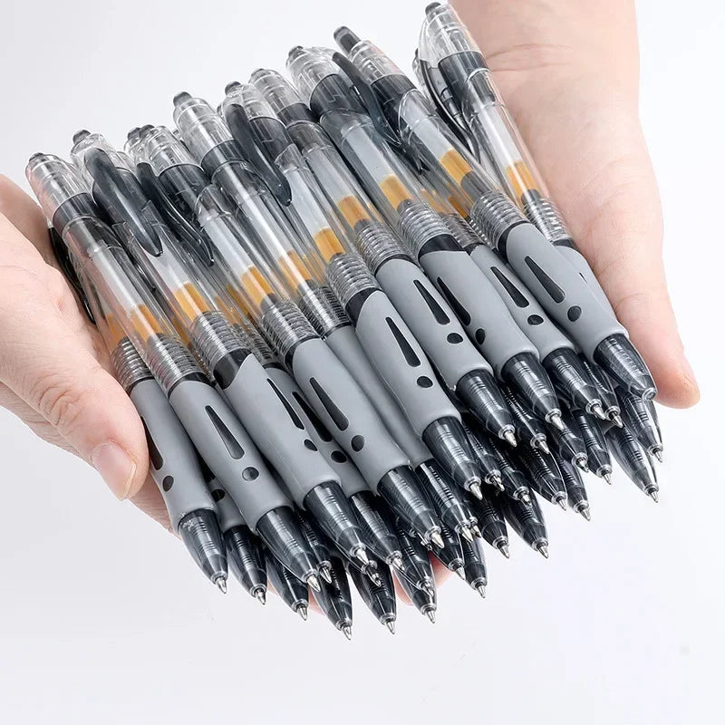 A hand holds a cluster of black and silver retractable gel pens with gold accents.