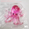 A pink squishy toy shaped like an octopus with glitter accents is sealed in a clear plastic bag.