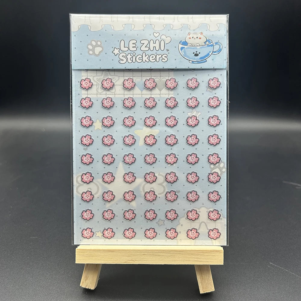 A vertical box of cute pink and blue decorative stickers for crafting and journaling displayed on a wooden stand.