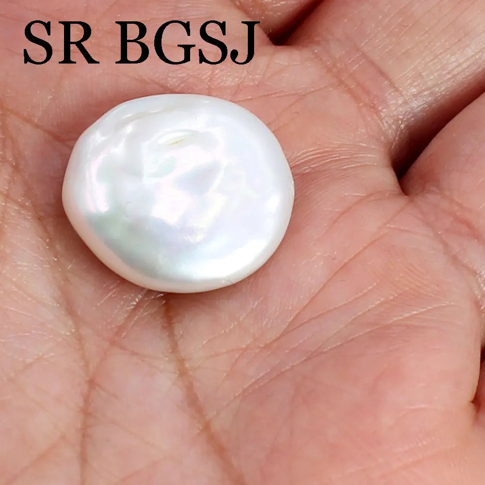 A smooth, round, iridescent white freshwater pearl bead resting on a person's hand.