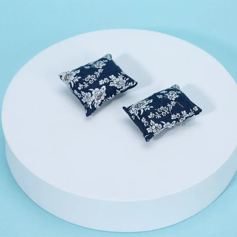 A pair of dark navy floral patterned cushions displayed on a white circular surface.