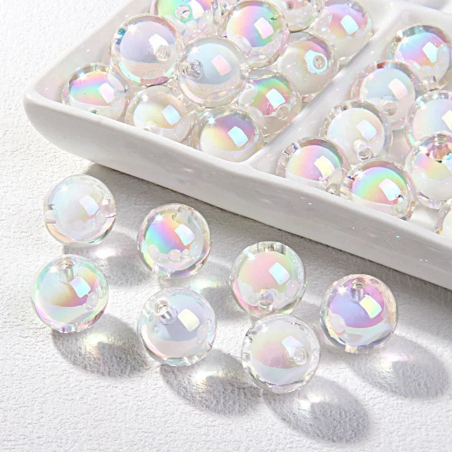A white dish filled with clear and iridescent acrylic craft beads for jewelry making