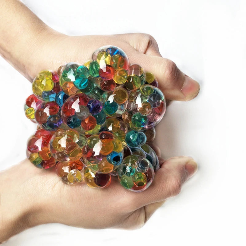 A hand holds a cluster of colorful, translucent stress relief balls with mesh netting.