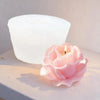 A pink silicone petal mold candle is placed in front of a large white candle holder.