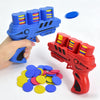 A hand holds a blue foam disc launcher toy, with several colored discs scattered nearby.