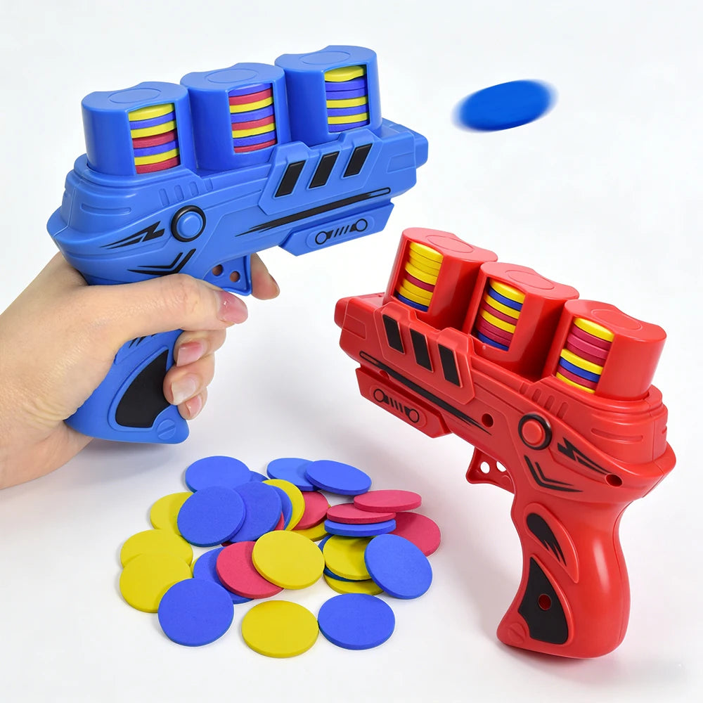 A hand holds a blue foam disc launcher toy, with several colored discs scattered nearby.