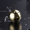 A polished gold metal fidget spinner resting on a dark, marbled surface.
