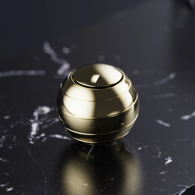 A polished gold metal fidget spinner resting on a dark, marbled surface.