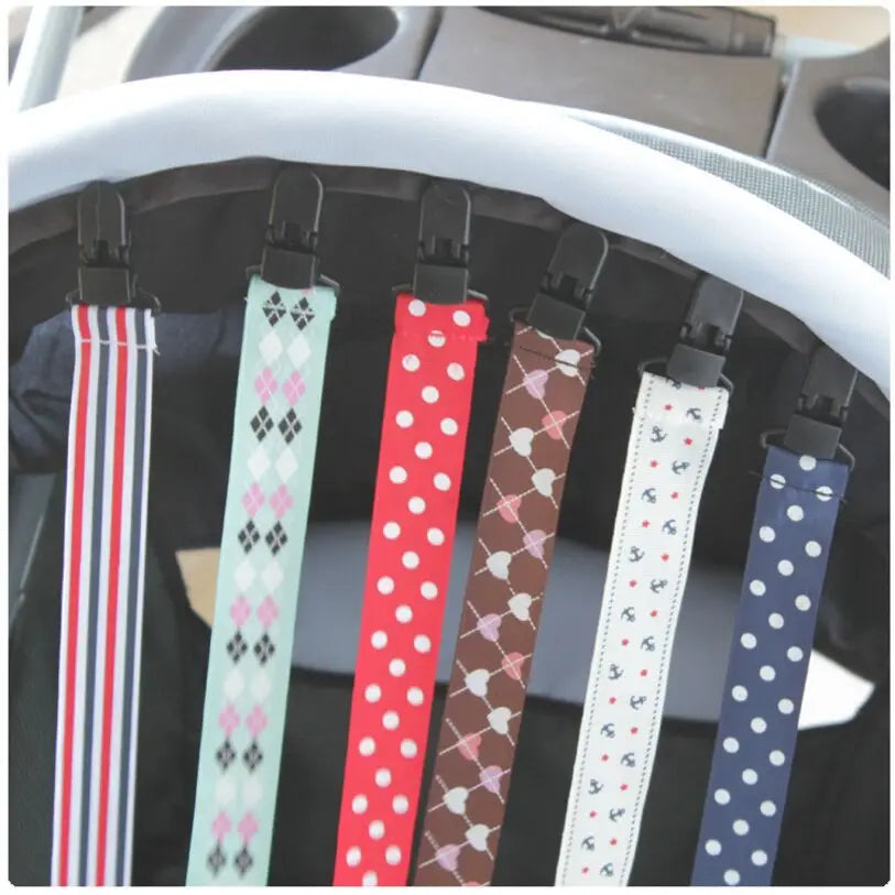 A set of four soft pacifier clips with double-sided prints featuring various patterns and colors.