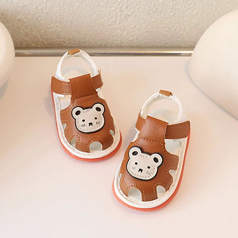 Une paire de sandales d'été antidérapantes pour bébés à motif ours brun, sur une surface claire.