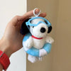 A white Snoopy plush charm wearing blue goggles and a red collar being held by a hand.