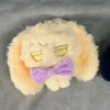 A fluffy yellow plush keychain featuring a face and a purple bow.