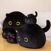 A black plush cat toy with yellow eyes is shown on a wooden surface.