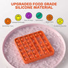 An orange silicone pop bubble sensory fidget toy is placed on a pink plate.