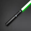 A black lightsaber toy with a glowing green blade and a metal handle is shown diagonally on a dark surface.