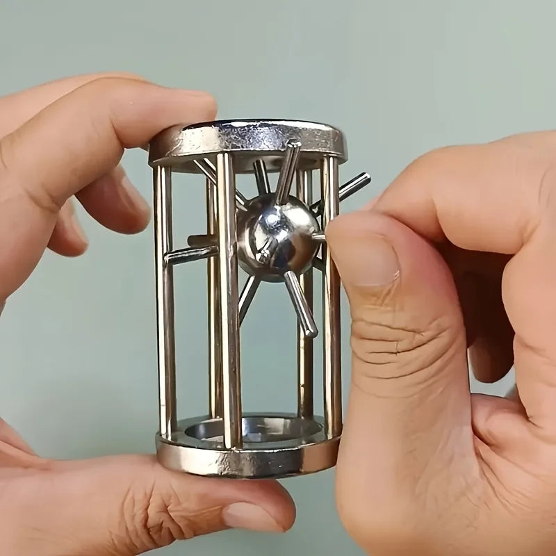 A hand holds a multi-layer stainless steel puzzle cage brain teaser with spiky metal rods inside.