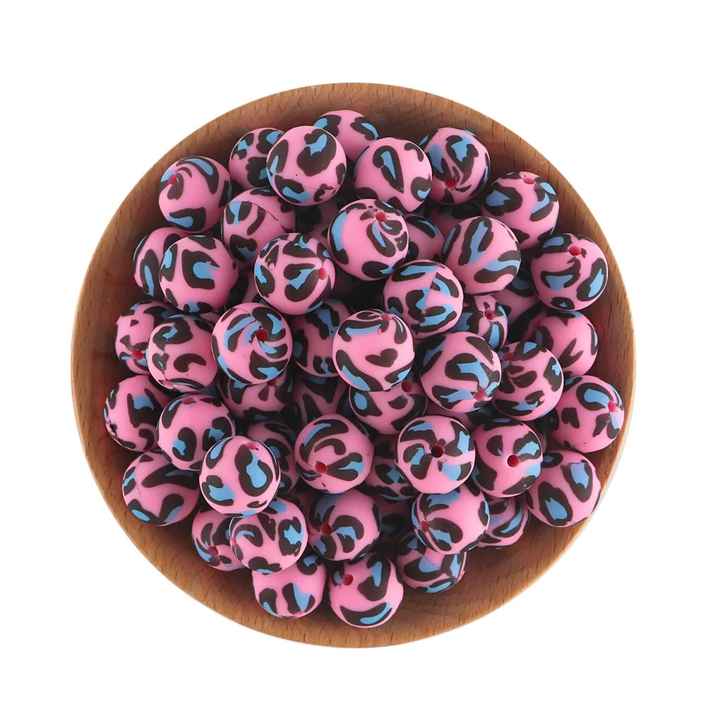 A pile of pink and blue leopard print silicone beads in a wooden bowl for jewelry making
