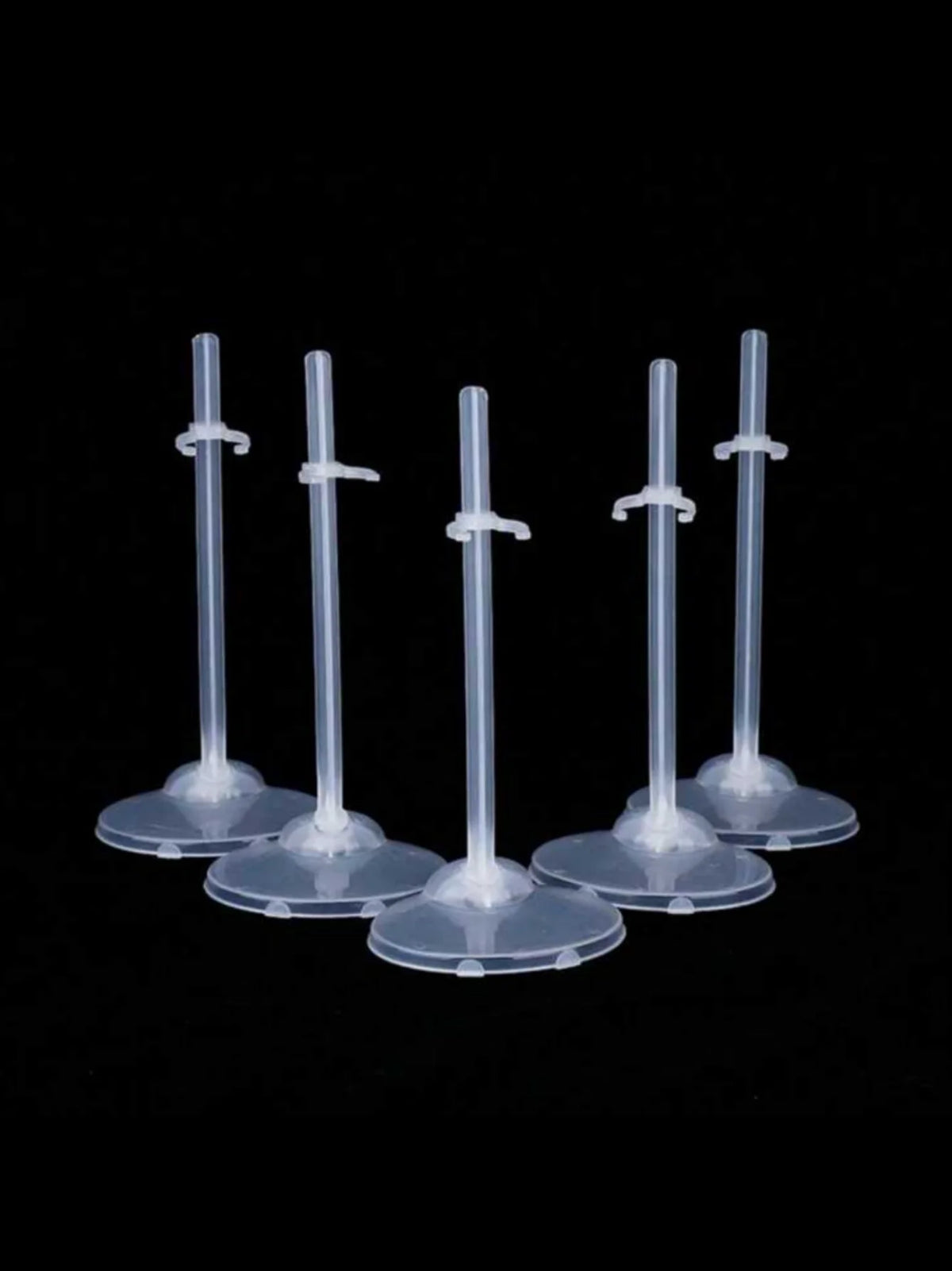 A set of transparent doll display stands with waist clips shown against a black background.