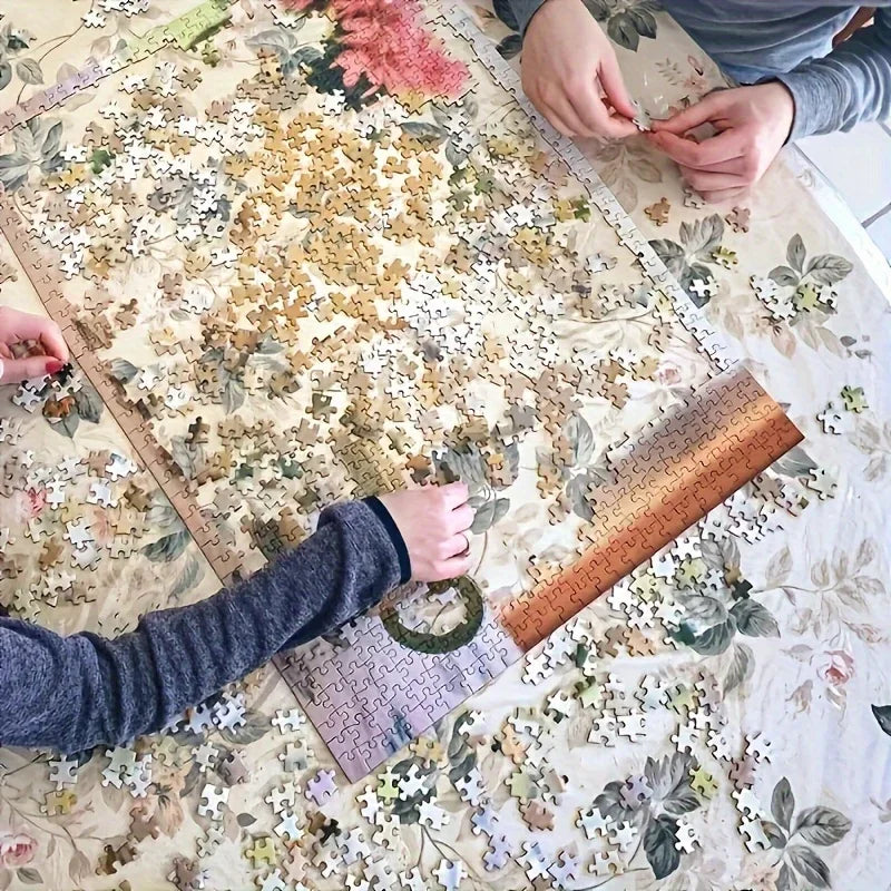 Hands are assembling an urban oil painting jigsaw puzzle for adults and families on a table.