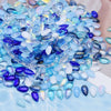 A pile of iridescent blue and purple water drop Czech glass beads for jewelry making