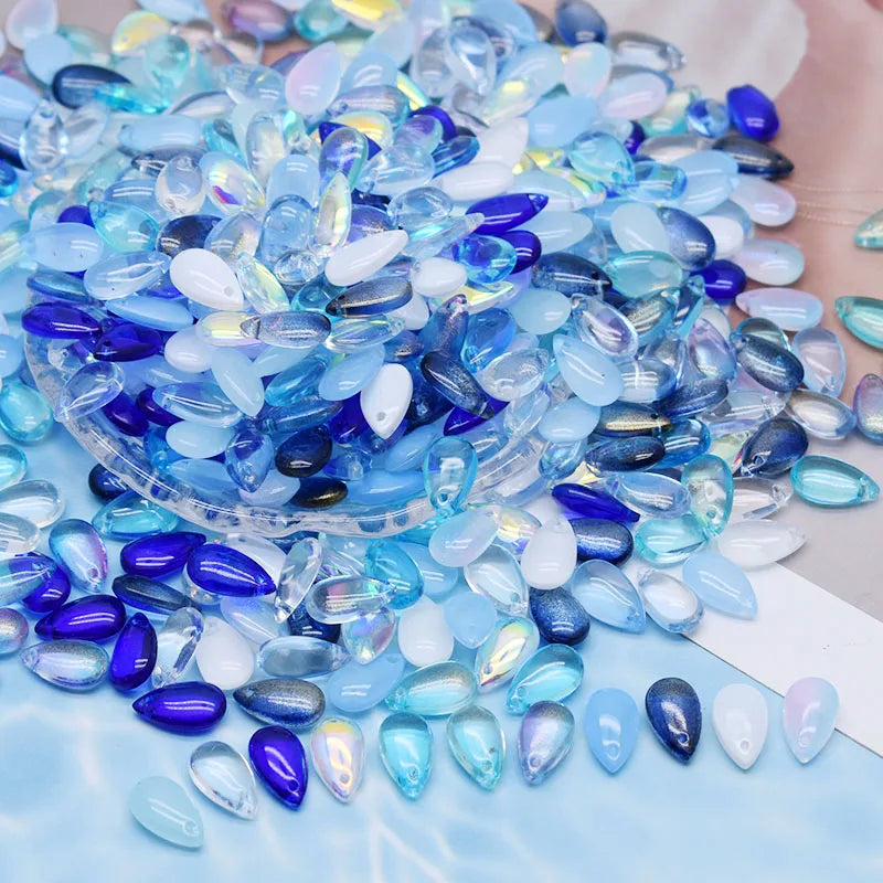 A pile of iridescent blue and purple water drop Czech glass beads for jewelry making