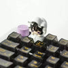 A close-up view of a black mechanical keyboard featuring Alien Stage Baby Series collectible keycaps and a white character fi