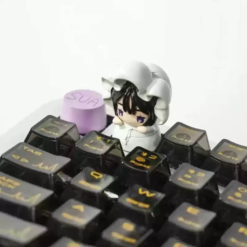 A close-up view of a black mechanical keyboard featuring Alien Stage Baby Series collectible keycaps and a white character fi
