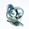 A clear silicone baby pacifier with a light blue translucent body and a gold rhinestone ring around the base.