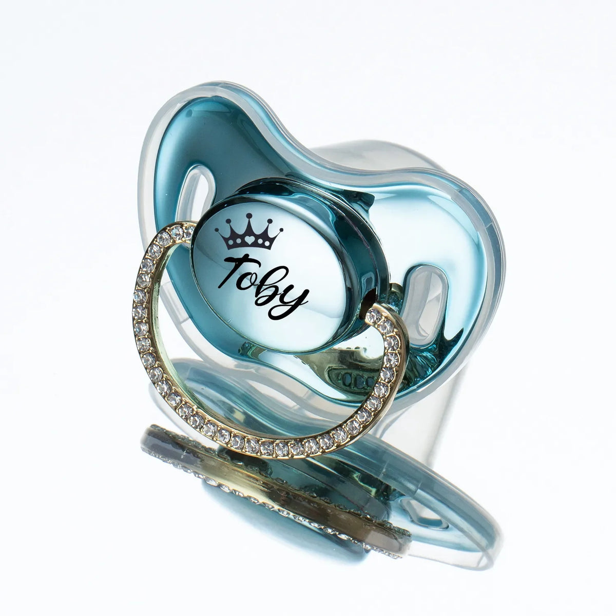 A clear silicone baby pacifier with a light blue translucent body and a gold rhinestone ring around the base.