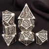 A set of seven polyhedral metal dice, including a d20 and dodecahedron, displayed on a dark surface.