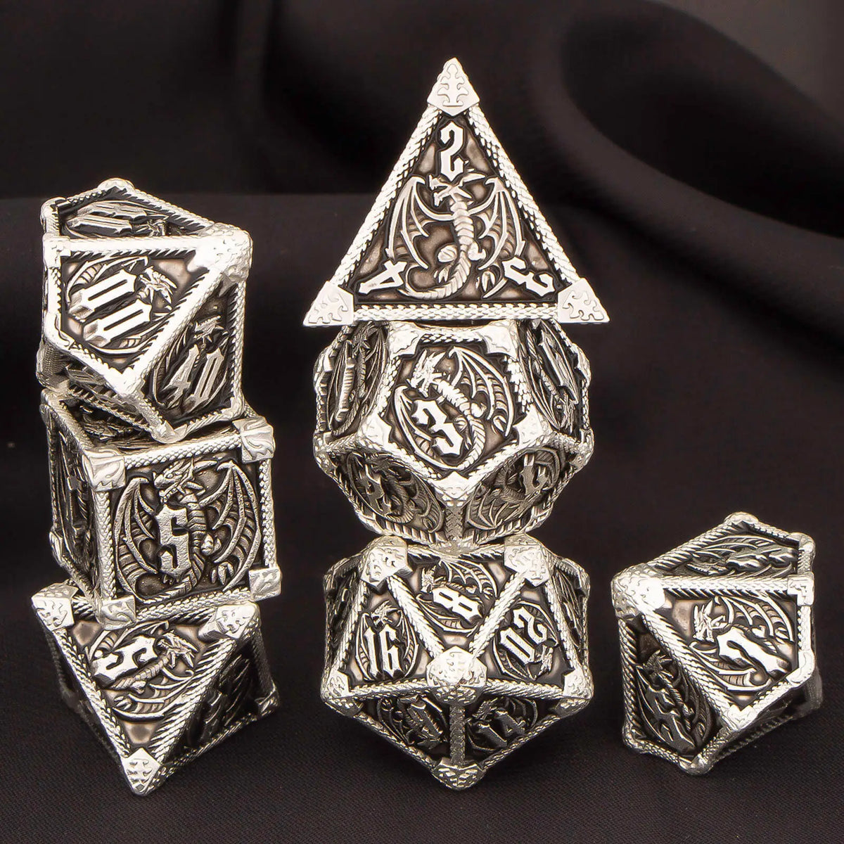 A set of seven polyhedral metal dice, including a d20 and dodecahedron, displayed on a dark surface.