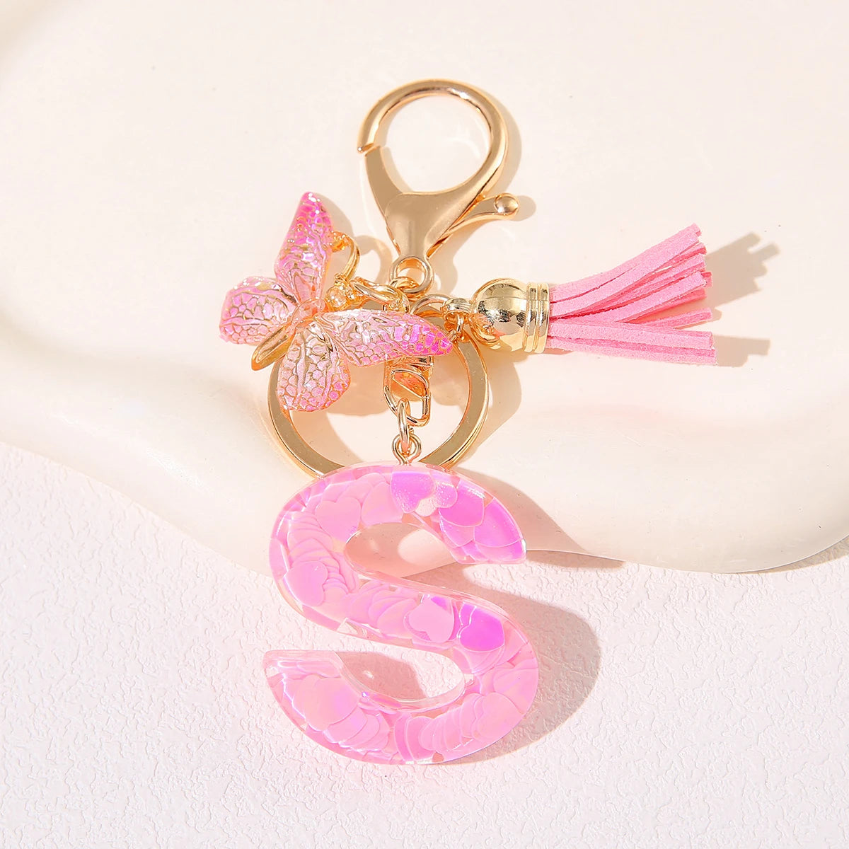 Gold heart keychain featuring a pink butterfly charm and a pink initial letter S.