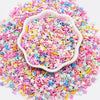 A pile of pink and multicolored polymer clay sprinkles scattered on a white background.