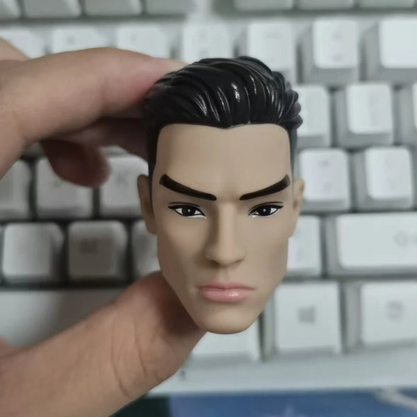 A hand is holding a 1/6 male doll's head accessory with dark hair and facial features against a keyboard background.