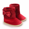 A pair of deep red velvet baby winter boots with matching bow accents.